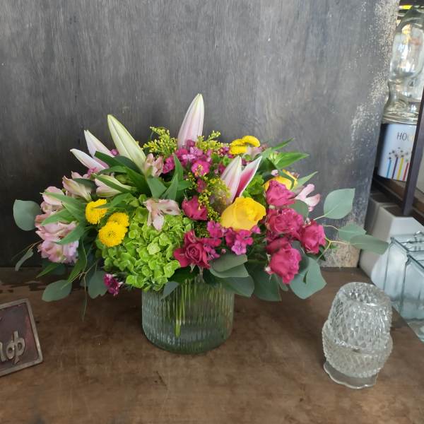 Mixed bouquet in a ribbed glass vase with pink, yellow, and white flowers