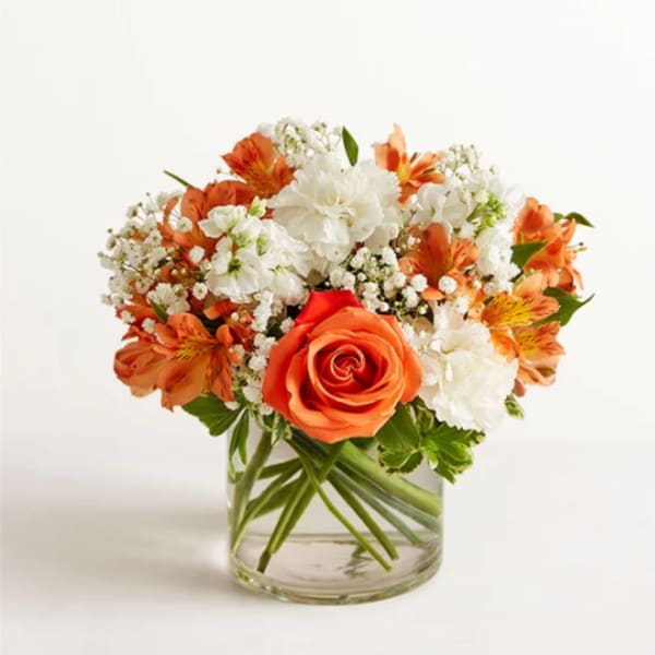 Orange and white mixed flower bouquet in a clear glass vase
