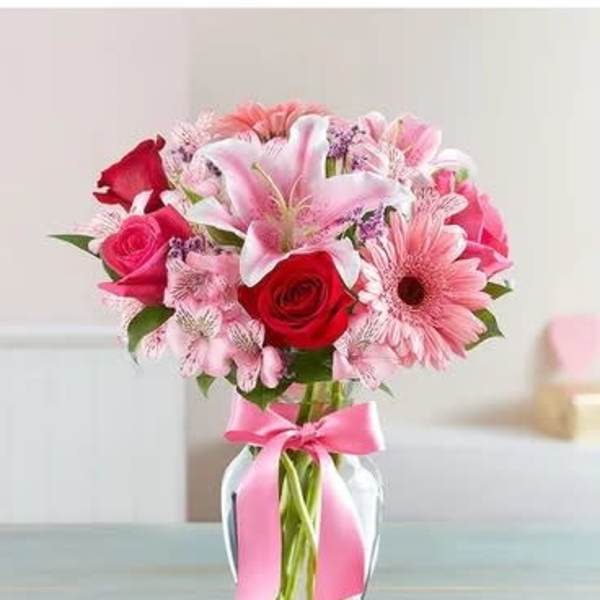 Pink and red mixed bouquet in a glass vase with a pink ribbon