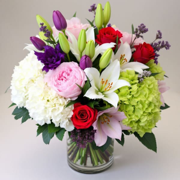 Bouquet of lilies, roses, hydrangeas, and peonies in a glass vase