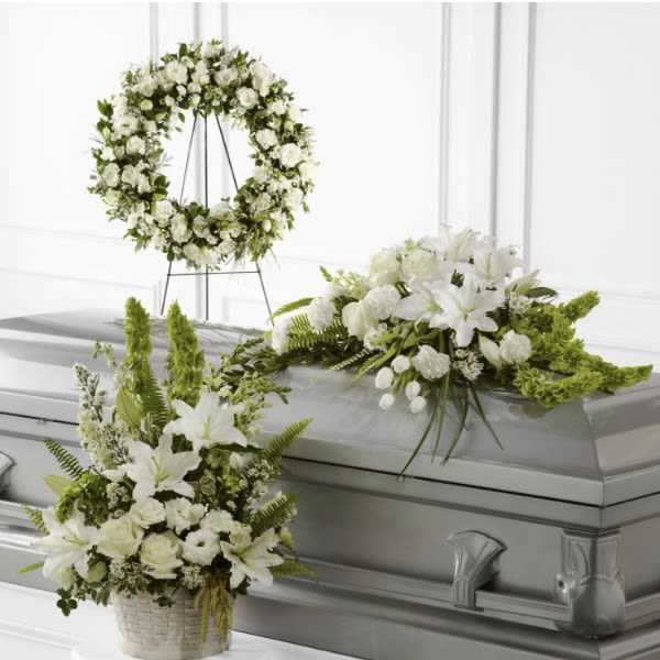 White floral funeral casket spray with matching wreath and basket arrangement