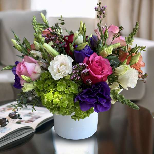 Mixed bouquet of roses, lisianthus, and hydrangea in a white vase