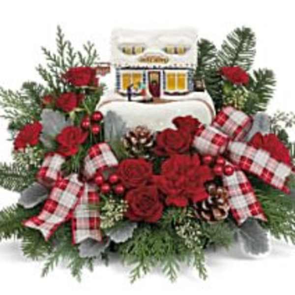 Christmas floral arrangement with red roses, plaid ribbons, and a small house ornament