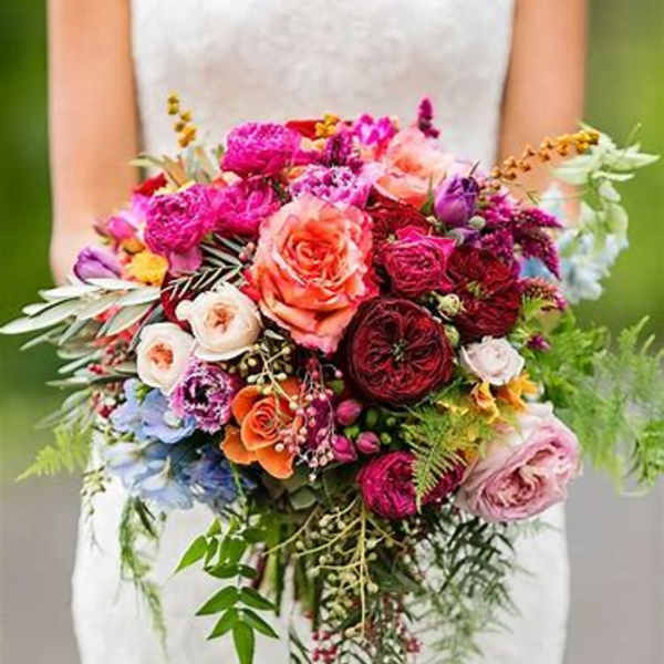 Bride holding a large colorful bouquet of roses and mixed flowers