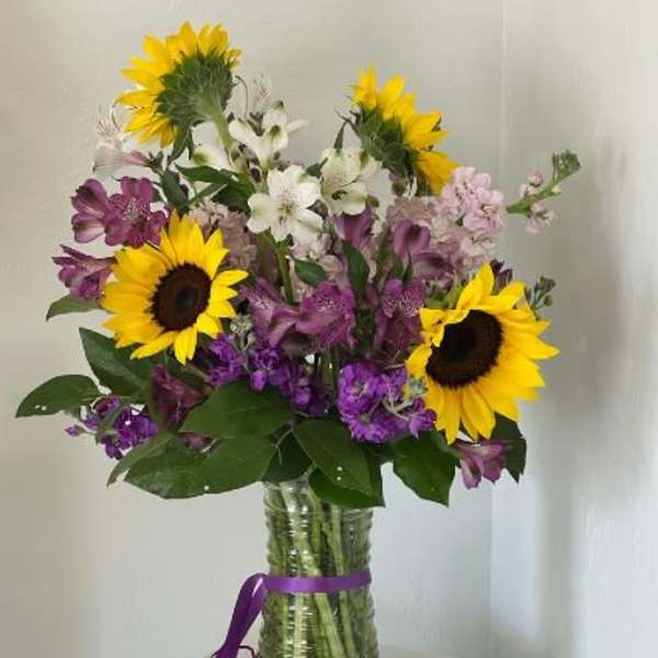 Bouquet of sunflowers, purple and white flowers in a glass vase