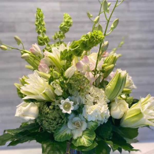 White and pale green floral arrangement in a dark vase