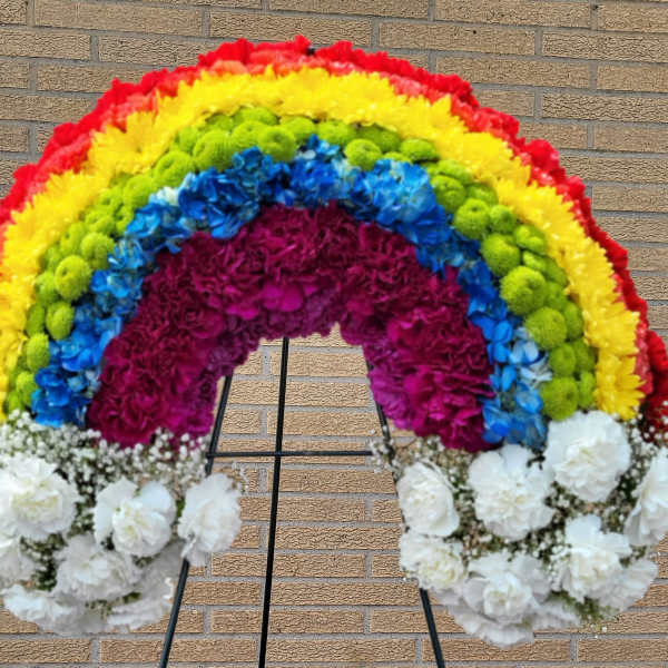 Rainbow floral standing spray on an easel with white flowers at the base