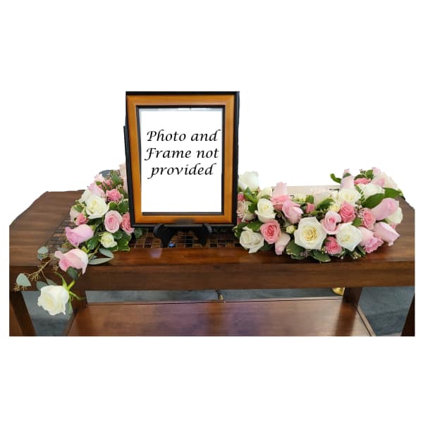 Pink and white rose arrangements flanking a framed sign on a table