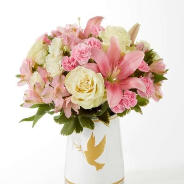 Pink and cream bouquet in a white vase with a gold dove design