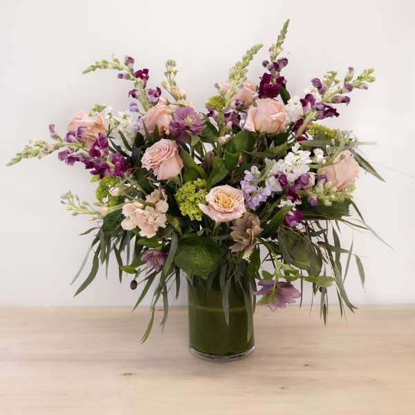 Mixed pink and purple flowers arranged in a glass vase