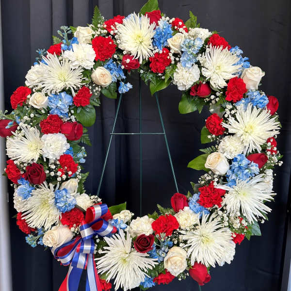 Large patriotic floral wreath with red, white, and blue flowers on a stand