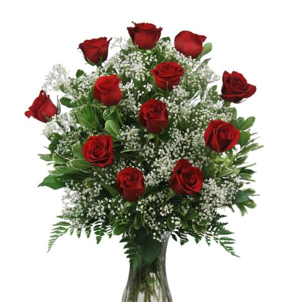 Red roses arranged in a clear glass vase with white filler flowers