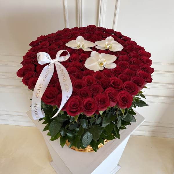 Large round arrangement of red roses with white orchids and a ribbon