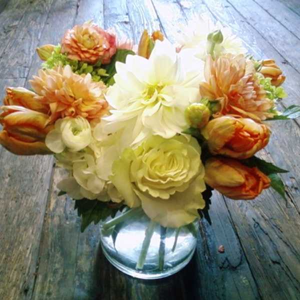 Bouquet of cream and orange flowers in a clear glass vase
