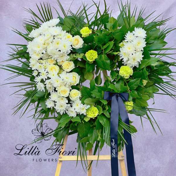 Heart-shaped floral wreath with white chrysanthemums and pale yellow roses on an easel