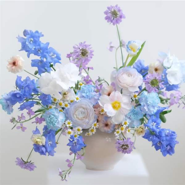 Pastel blue and lavender floral arrangement in a pale vase