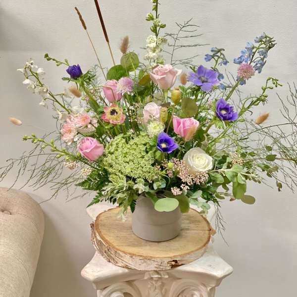 Loose pastel bouquet in a white vase with pink, purple, and white blooms