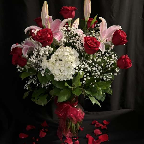 Bouquet of red roses and pink lilies with white hydrangea in a glass vase