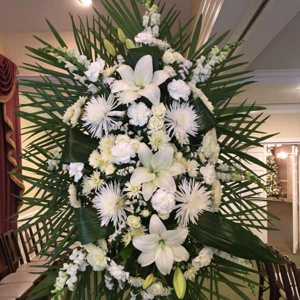 Large white funeral spray with lilies and chrysanthemums on a stand