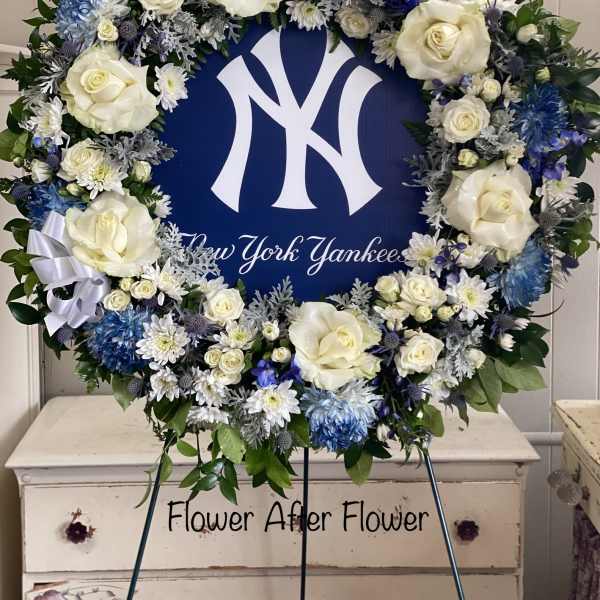 Round floral wreath with white roses and blue flowers around a New York Yankees sign