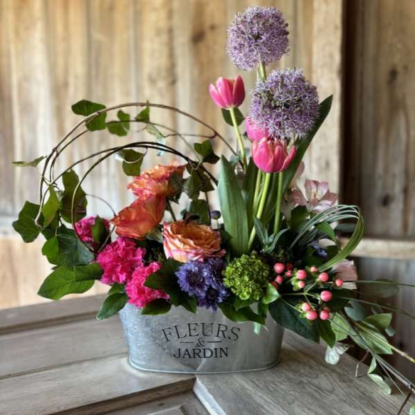 Mixed bouquet in a metal container with pink, purple, and orange flowers