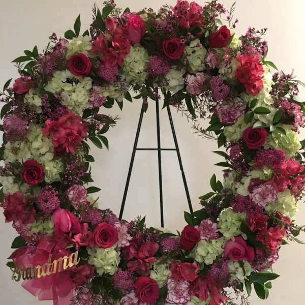 Large floral wreath with pink and white flowers on a black stand
