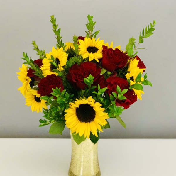 Bouquet of red roses and yellow sunflowers in a gold vase