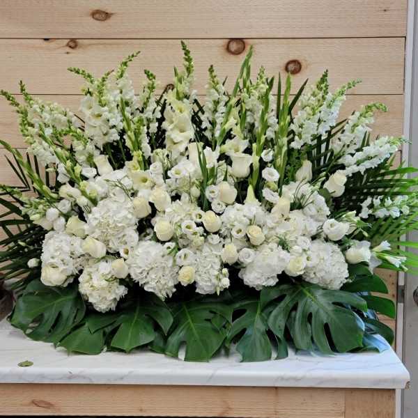 Large white floral arrangement with tall spikes and broad green leaves