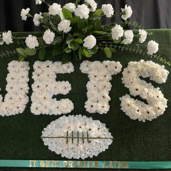 White floral letters on a green board with a football shape below