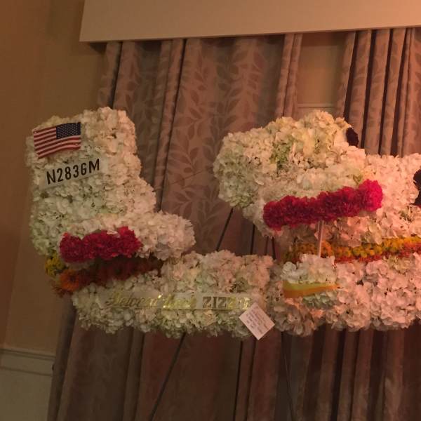Large floral airplane display made of white flowers with colored accents