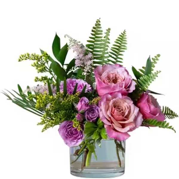 Pink and purple roses in a clear glass vase with fern foliage