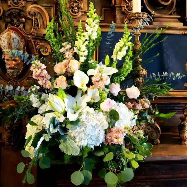 Large white floral arrangement with lilies, calla lilies, and pastel blooms