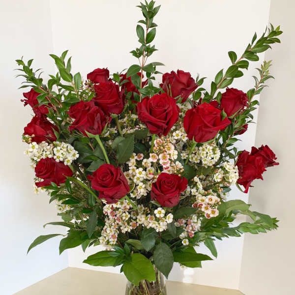 Red roses and white filler flowers in a clear glass vase
