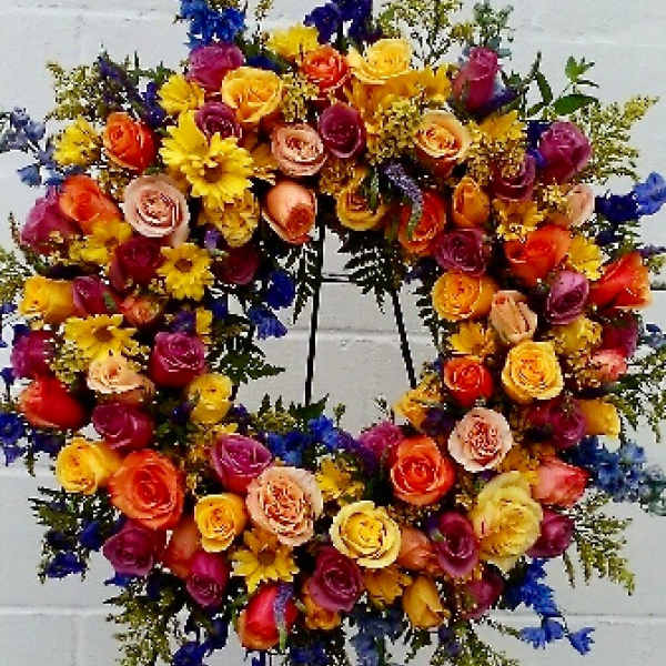 Colorful floral wreath on a stand with roses and daisies