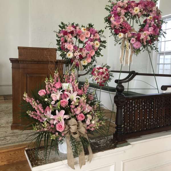 Pink floral wreaths and a large bouquet arranged in a church interior
