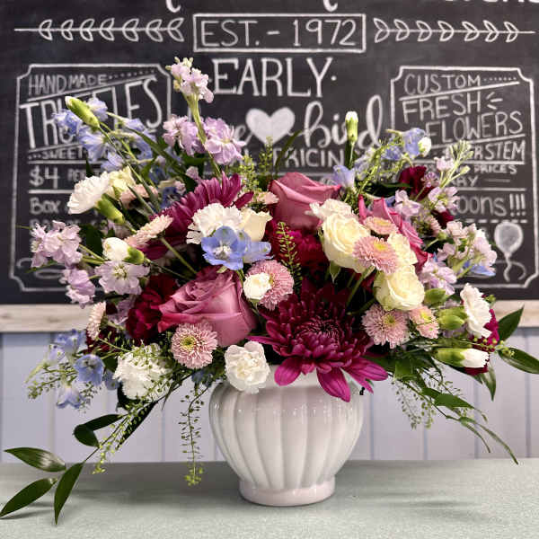 Mixed pink, white, and blue flowers arranged in a white vase
