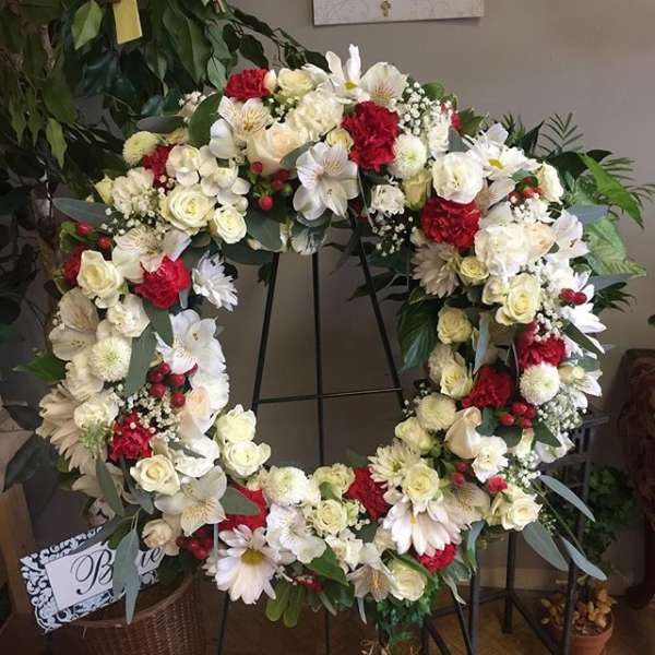 Heart-shaped floral wreath with white and red flowers on a stand