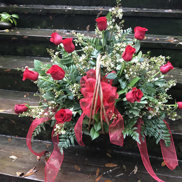 Arrangement of red roses with white filler flowers and red ribbon