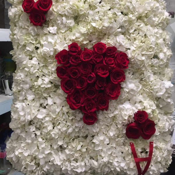 White floral heart display with red roses and ribbon accents