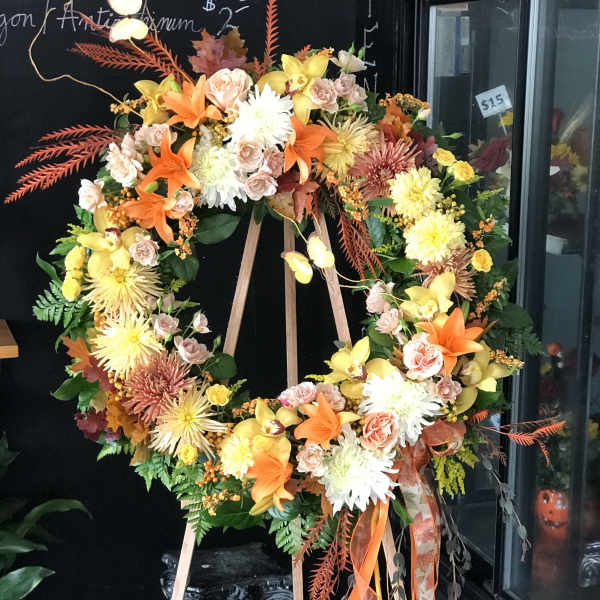 Large floral wreath on an easel with orange, yellow, and pink flowers