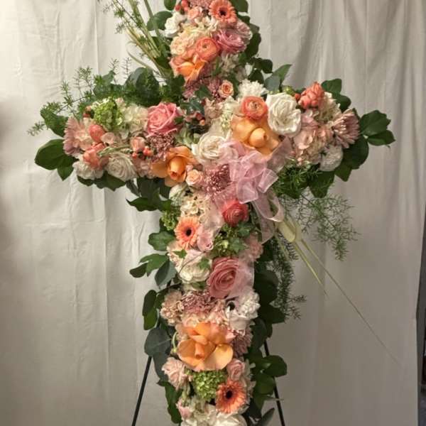 Cross-shaped floral spray with pink, peach, and white flowers on a stand