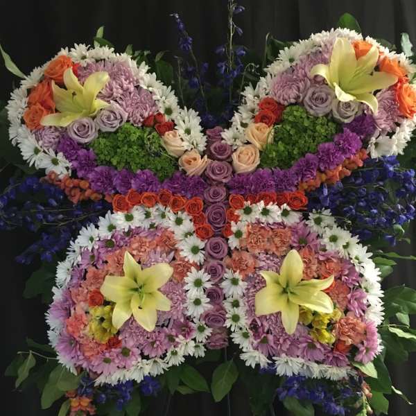 Butterfly-shaped floral arrangement with lilies, roses, and daisies