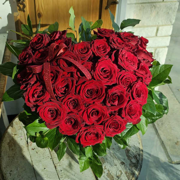 Heart-shaped bouquet of red roses with a red ribbon