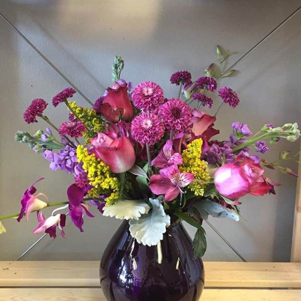 Pink and purple mixed bouquet in a dark glass vase