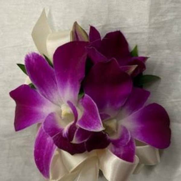 Purple orchid corsage with cream ribbon on a light fabric background