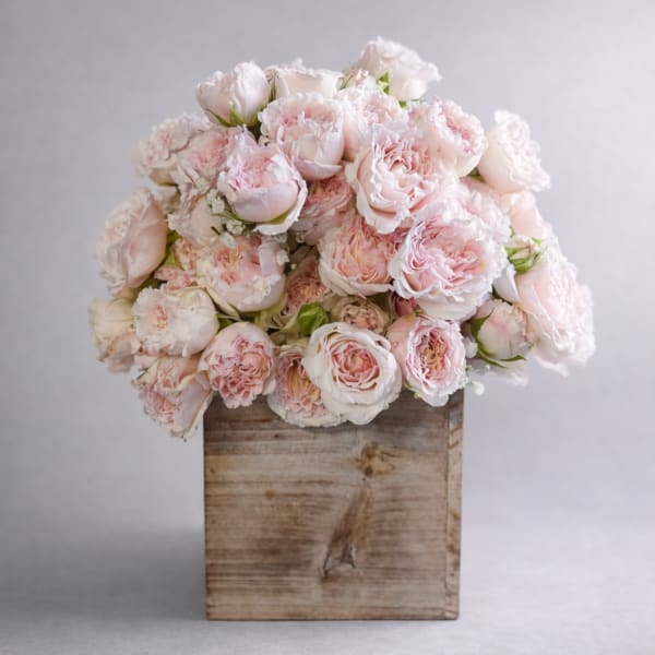 Bouquet of pale pink roses in a rustic wooden box