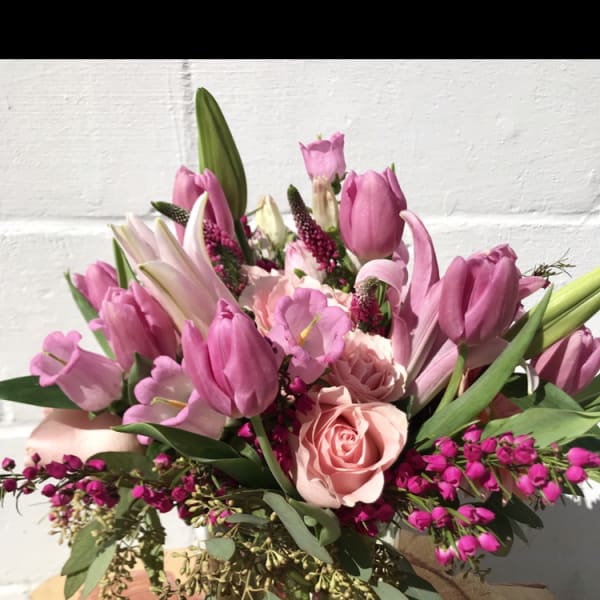 Pink tulips and roses arranged in a clear glass vase