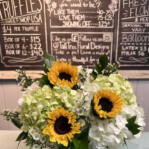 Sunflowers and white hydrangeas arranged in a glass vase