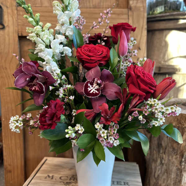 Red roses and burgundy orchids in a white vase