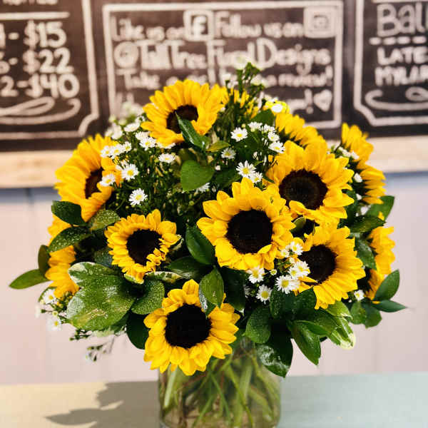 Bouquet of yellow sunflowers and small white daisies in a glass vase